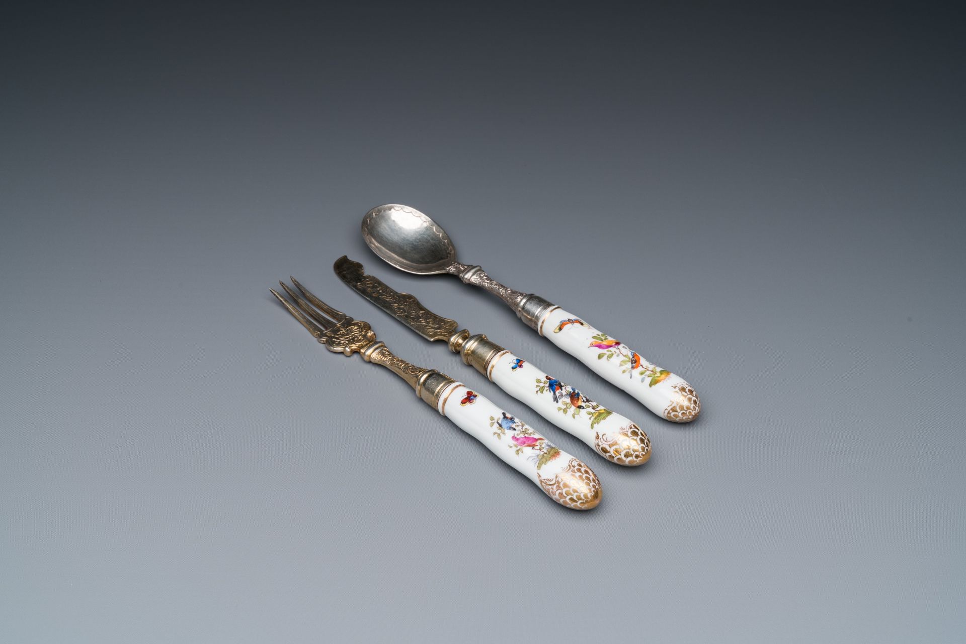Three polychrome and gilt Meissen porcelain fork, knife and spoon handles with birds and butterflies