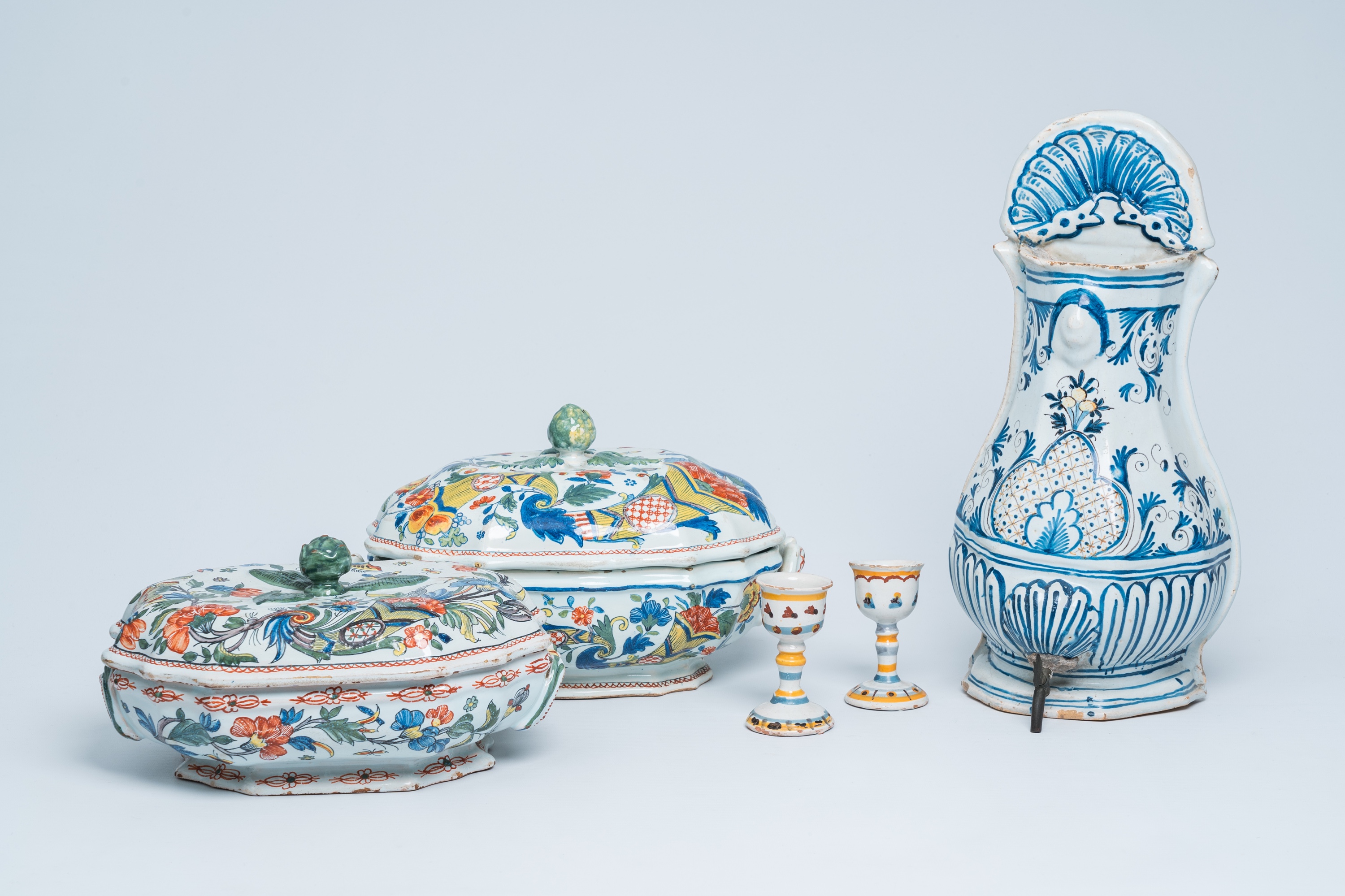 Two polychrome French Rouen faience tureens and covers, a pair of egg cups and a wall fountain, 18th