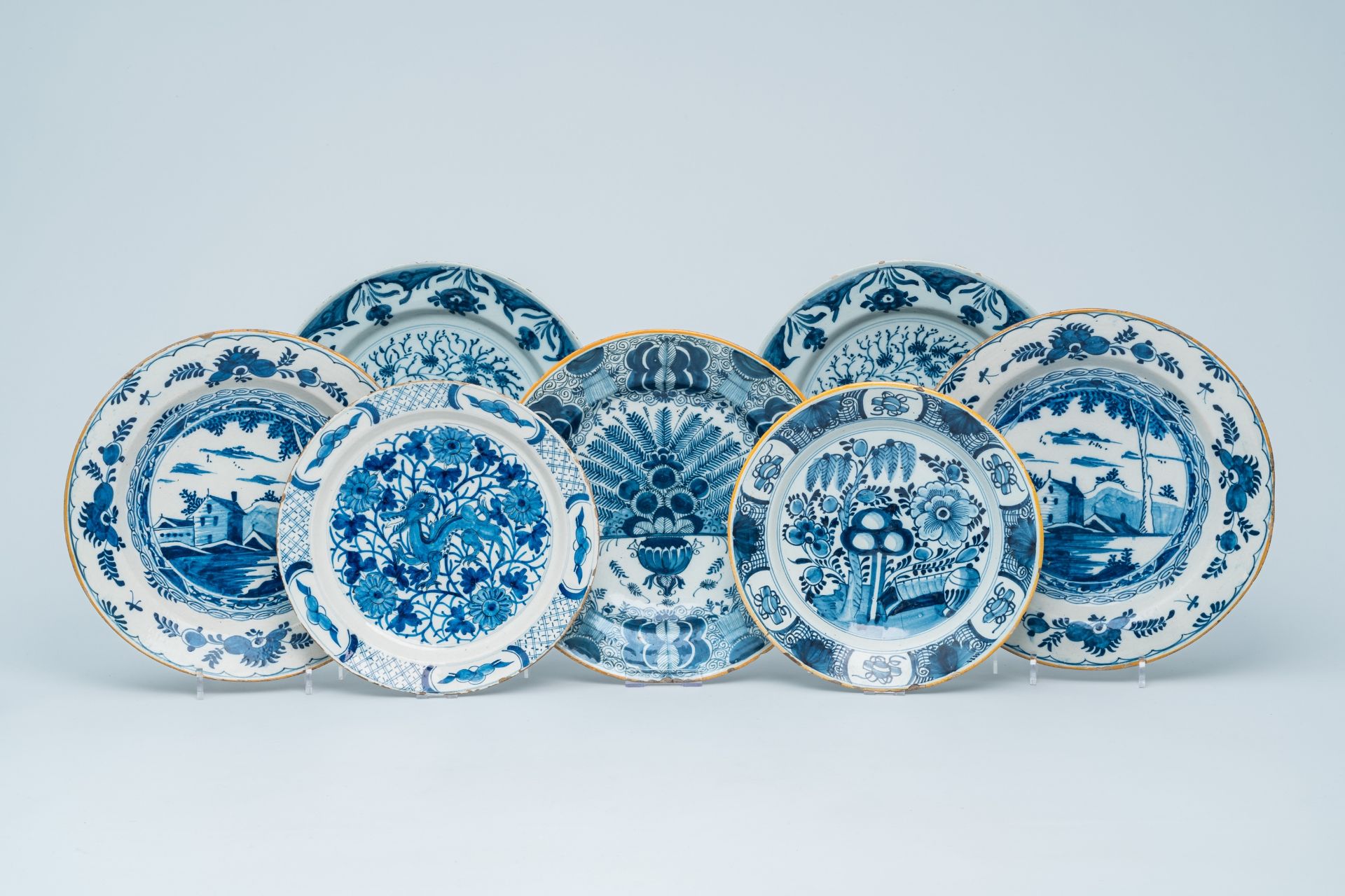 Seven various Dutch Delft blue and white chargers with landscapes, a dragon and floral design, 18th