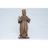 A large wood sculpture of Saint Damian holding a book and an ointment jar, Central Europe, 17th C.