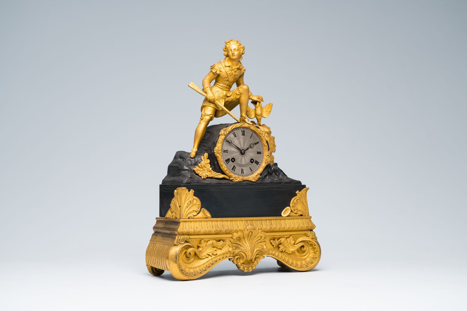 A French gilt and patinated bronze mantel clock topped with a hunter and his prey, 19th C.