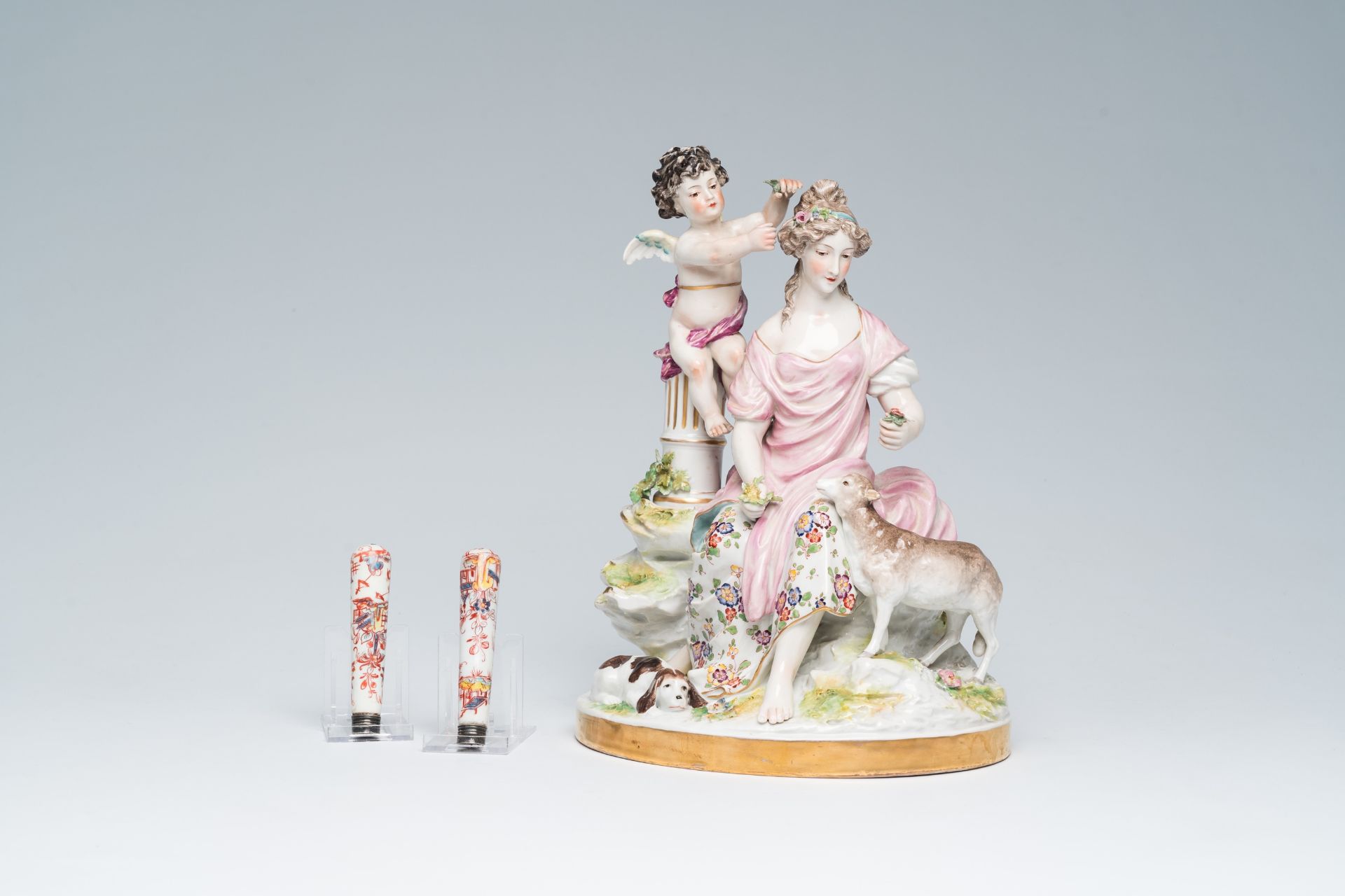 A pair of French polychrome Mennecy knife handles and a Saxon porcelain group with a lady and an ang