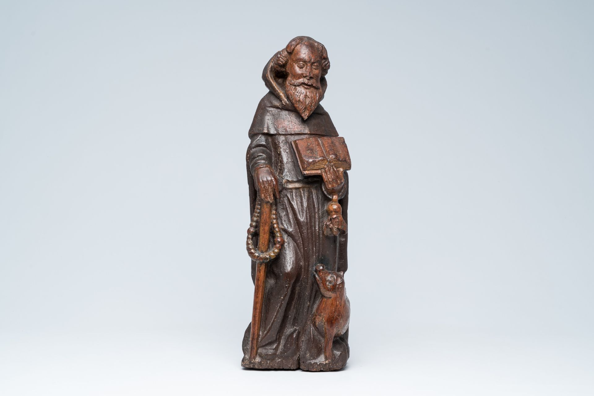 A Flemish carved oak figure of Saint Anthony the Great with traces of polychromy, 15th/16th C.