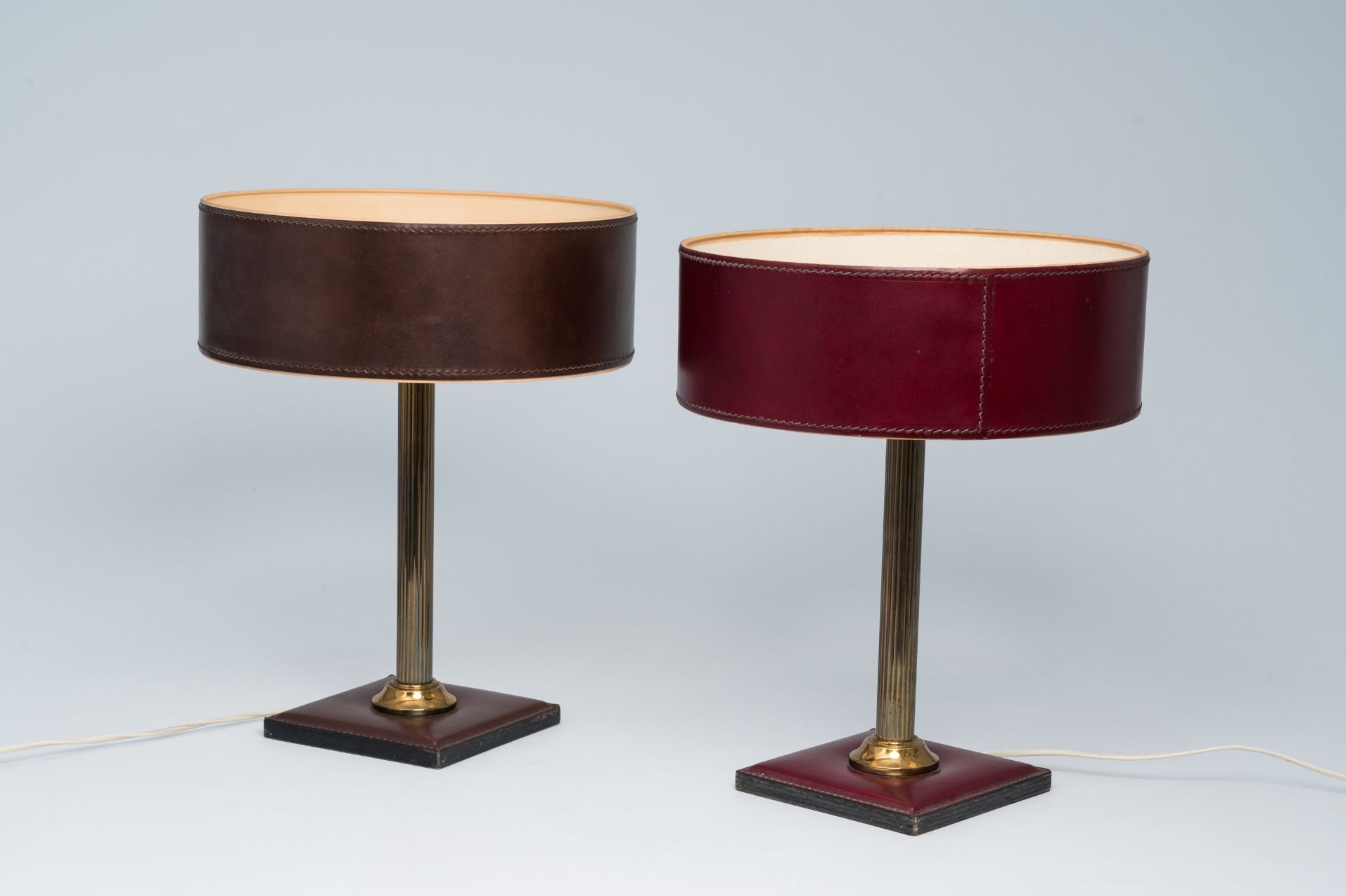 A pair of French brass and leather clad desk lamps after a design by Jacques Adnet, third quarter 20