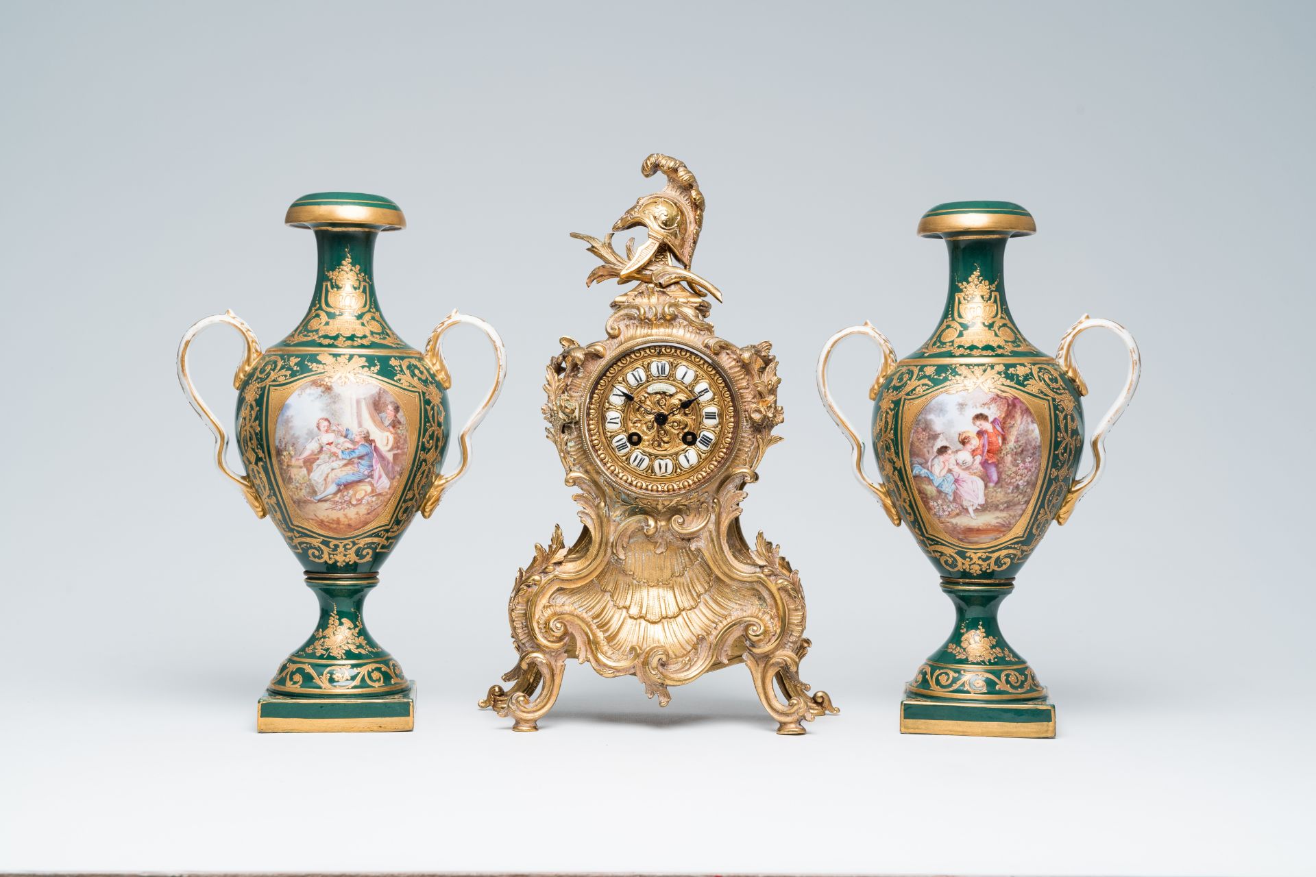 A French Louis XV style brass mantel clock and a pair of gold layered green ground Sevres style vase