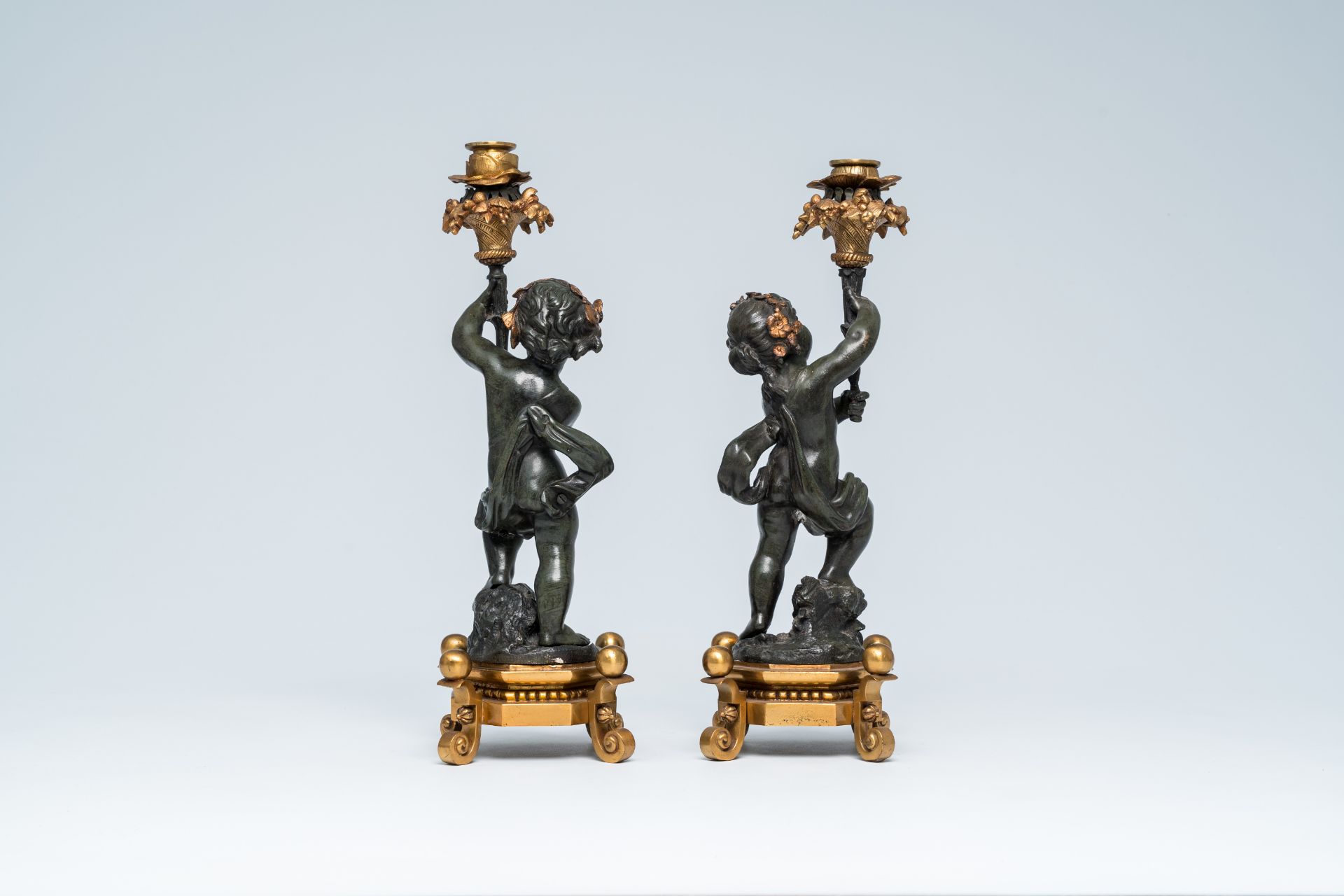 A pair of French gilt and patinated bronze candlesticks carried by putti, 19th/20th C. - Image 4 of 7