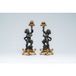 A pair of French gilt and patinated bronze candlesticks carried by putti, 19th/20th C.