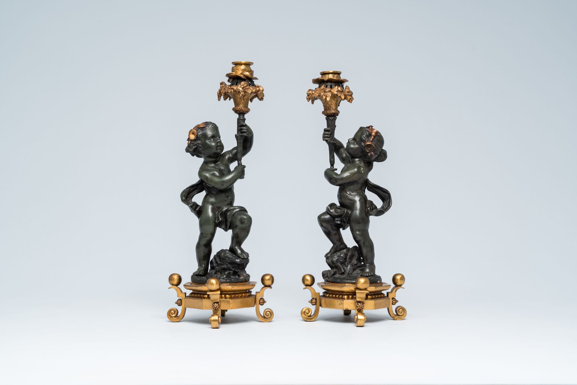 A pair of French gilt and patinated bronze candlesticks carried by putti, 19th/20th C.