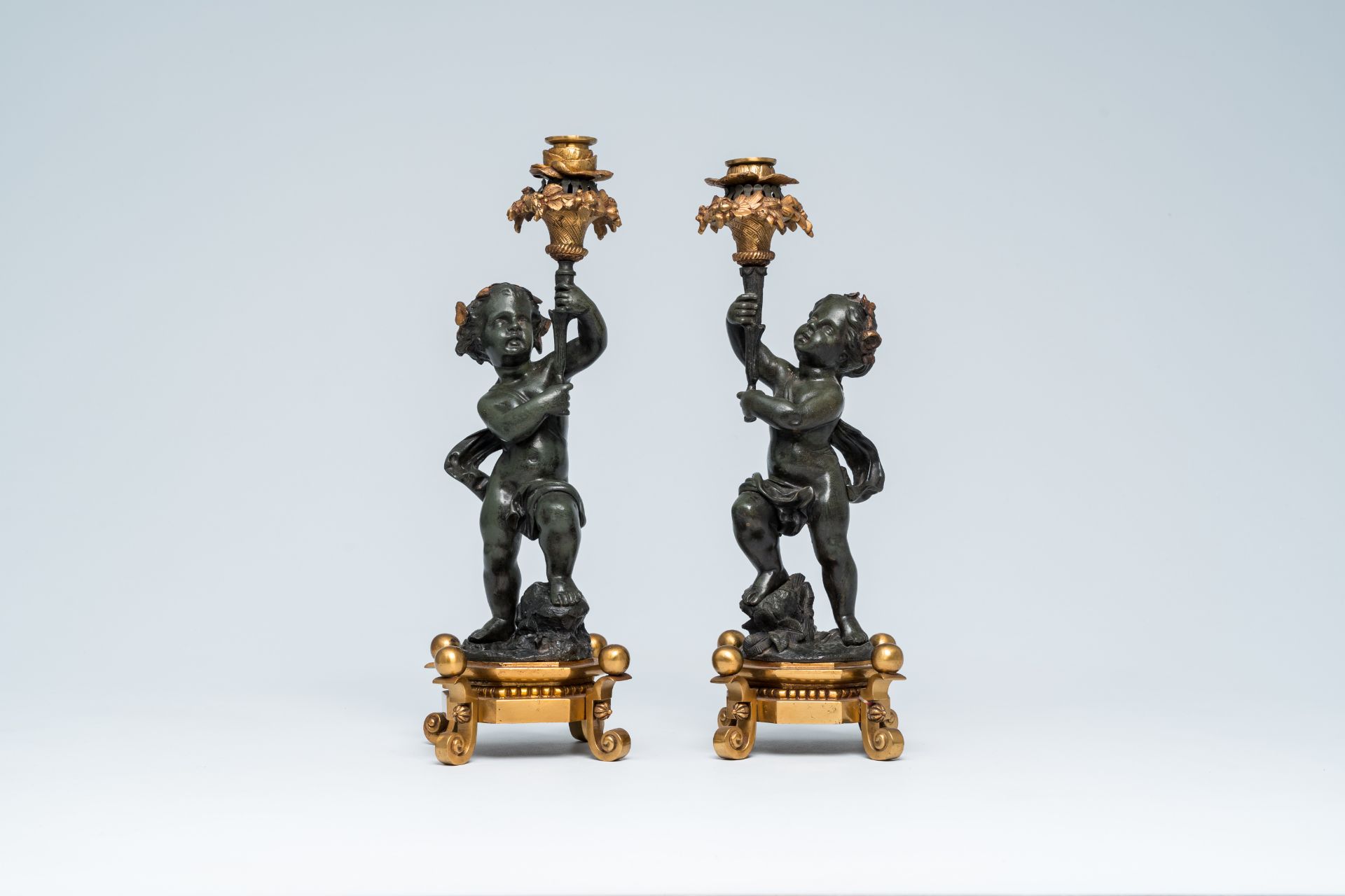 A pair of French gilt and patinated bronze candlesticks carried by putti, 19th/20th C. - Image 2 of 7