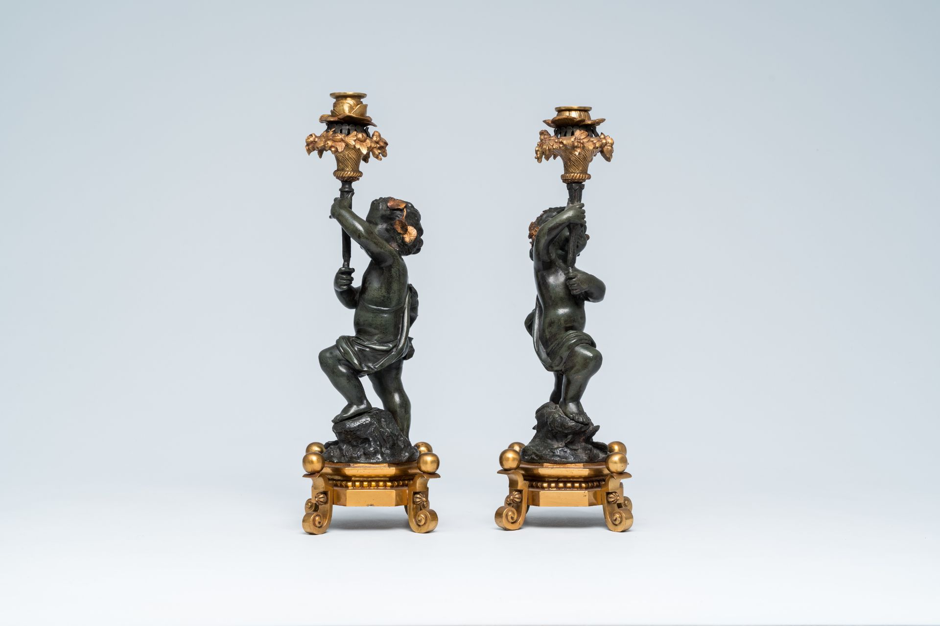 A pair of French gilt and patinated bronze candlesticks carried by putti, 19th/20th C. - Image 3 of 7