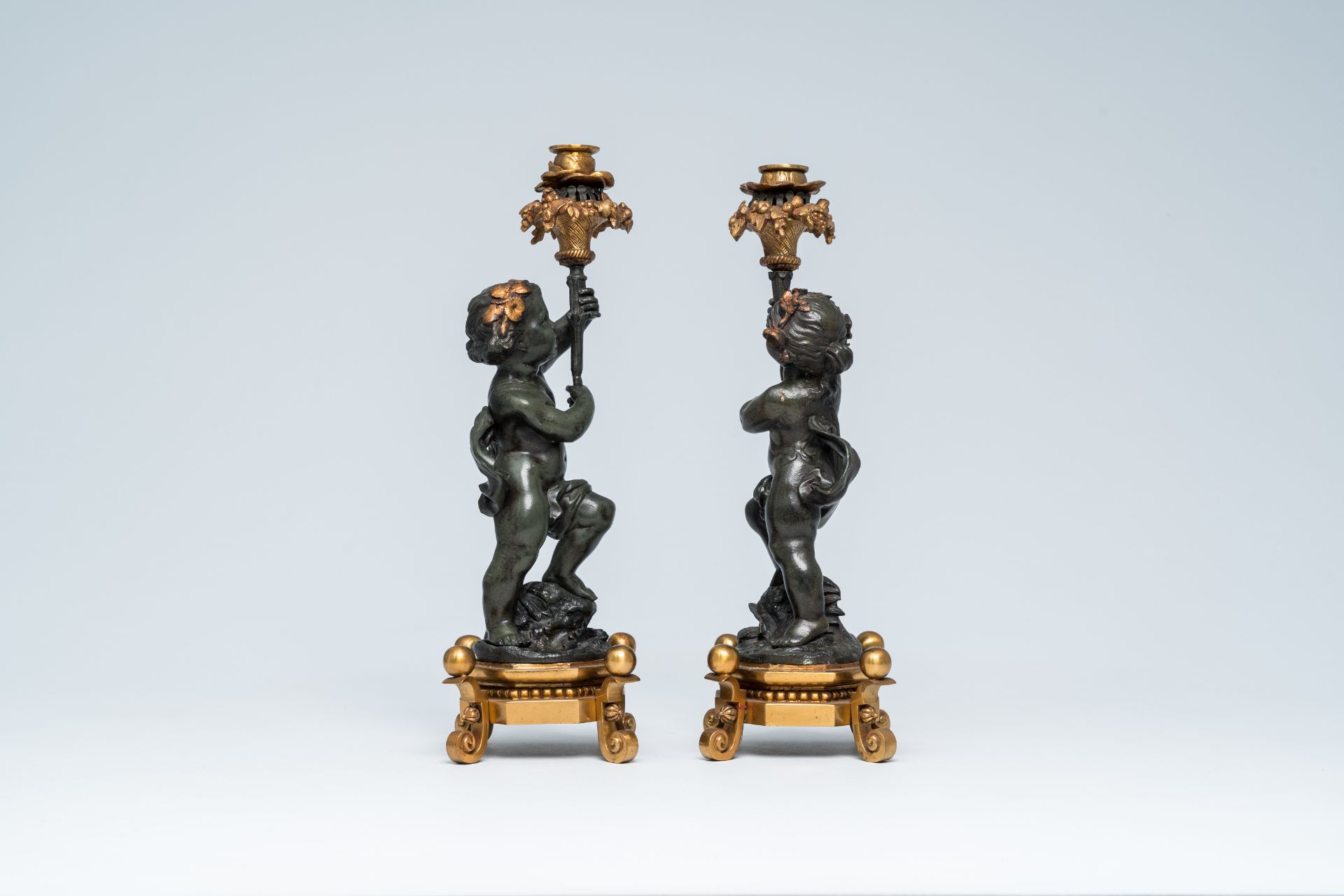 A pair of French gilt and patinated bronze candlesticks carried by putti, 19th/20th C. - Image 5 of 7