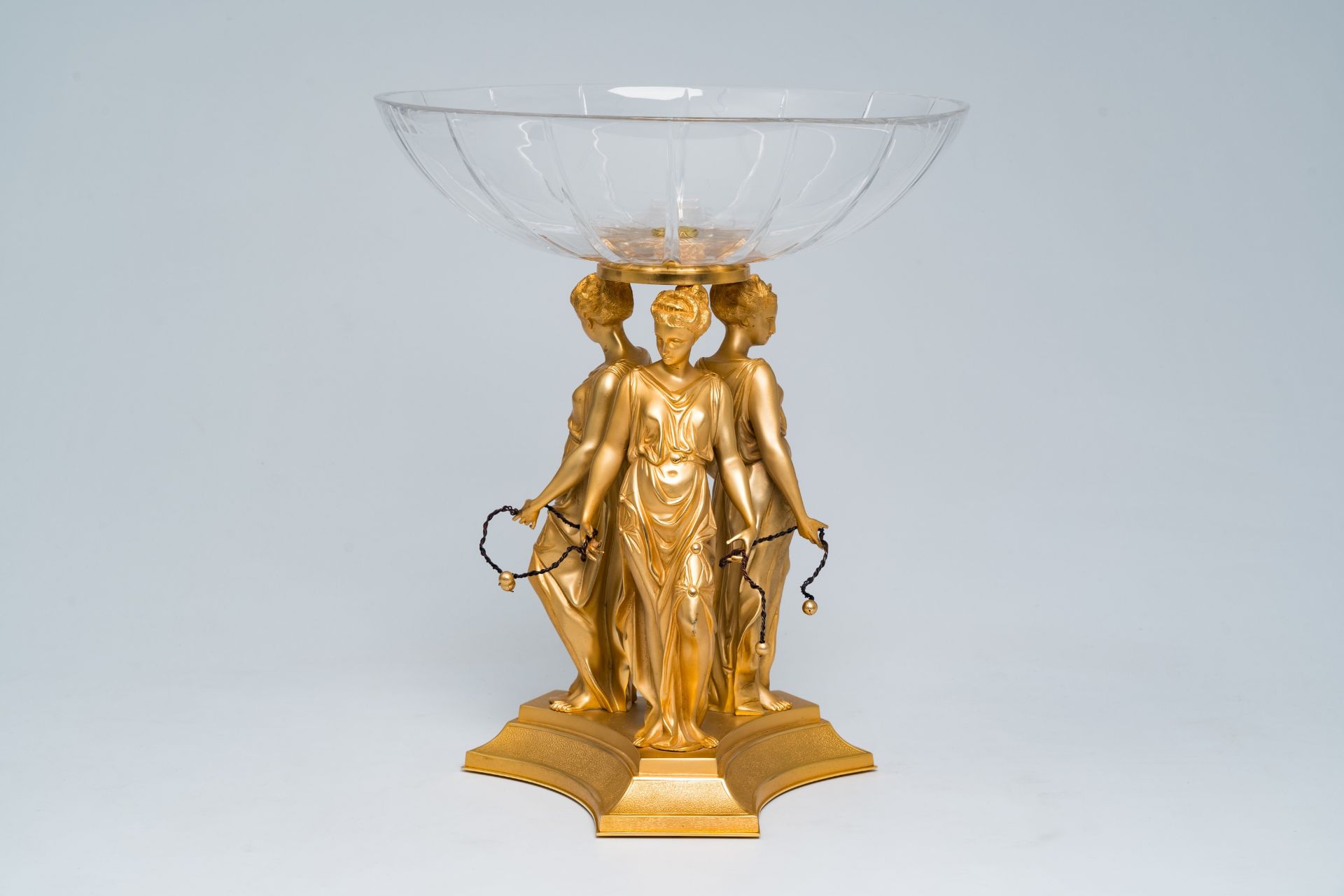 A lavish table centrepiece consisting of a decorative crystal bowl worn by the three graces in gilt