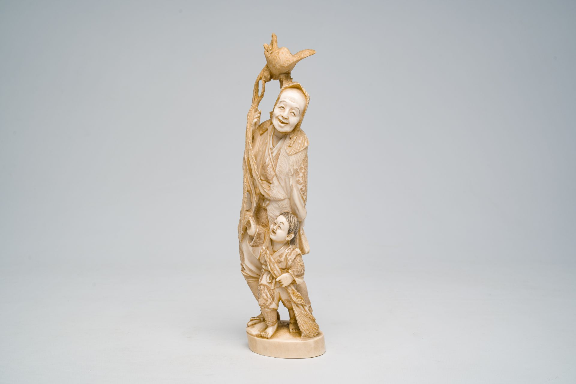 A Japanese ivory okimono of a laughing man with a child and a rooster, signed, Meiji, ca. 1900