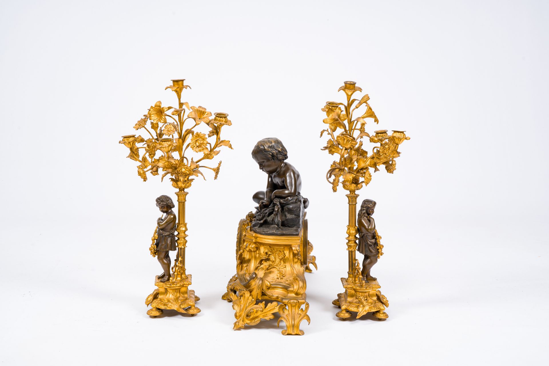 A French gilt and patinated bronze three-piece clock garniture crowned with a putto playing with a b - Image 3 of 5