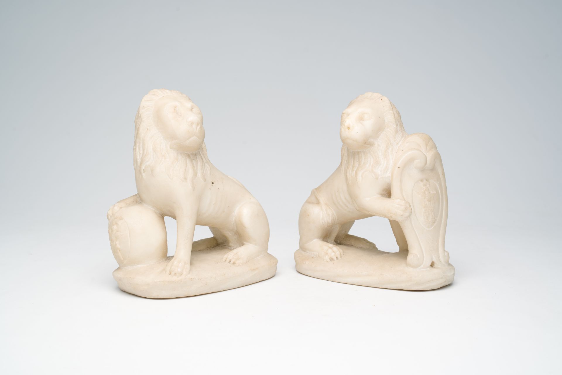 A pair of Italian marble lions holding shields with coats of arms, 19th C.