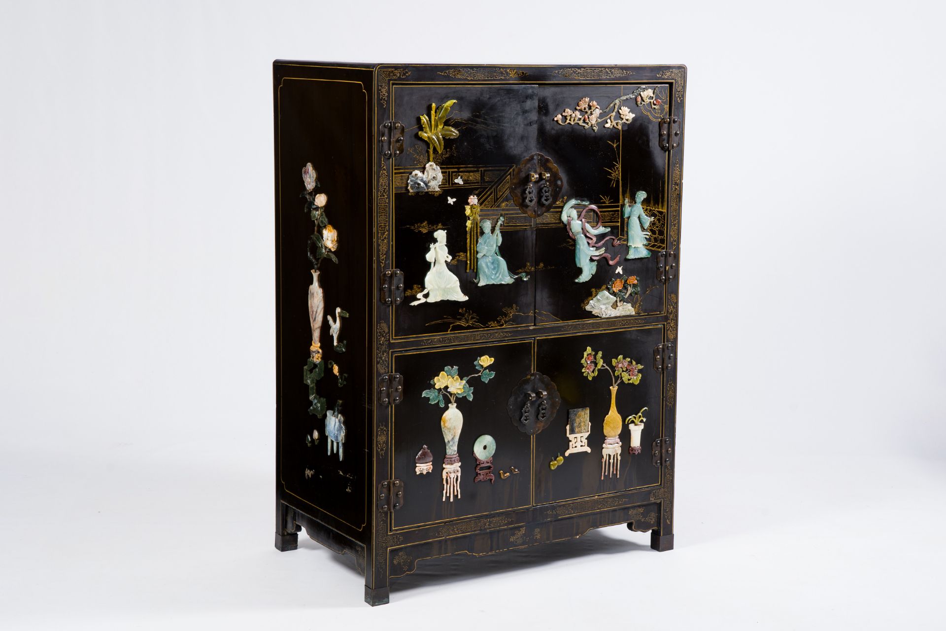 A Chinese lacquered wood cabinet inlaid with semi-precious stones showing ladies on a terrace, flowe