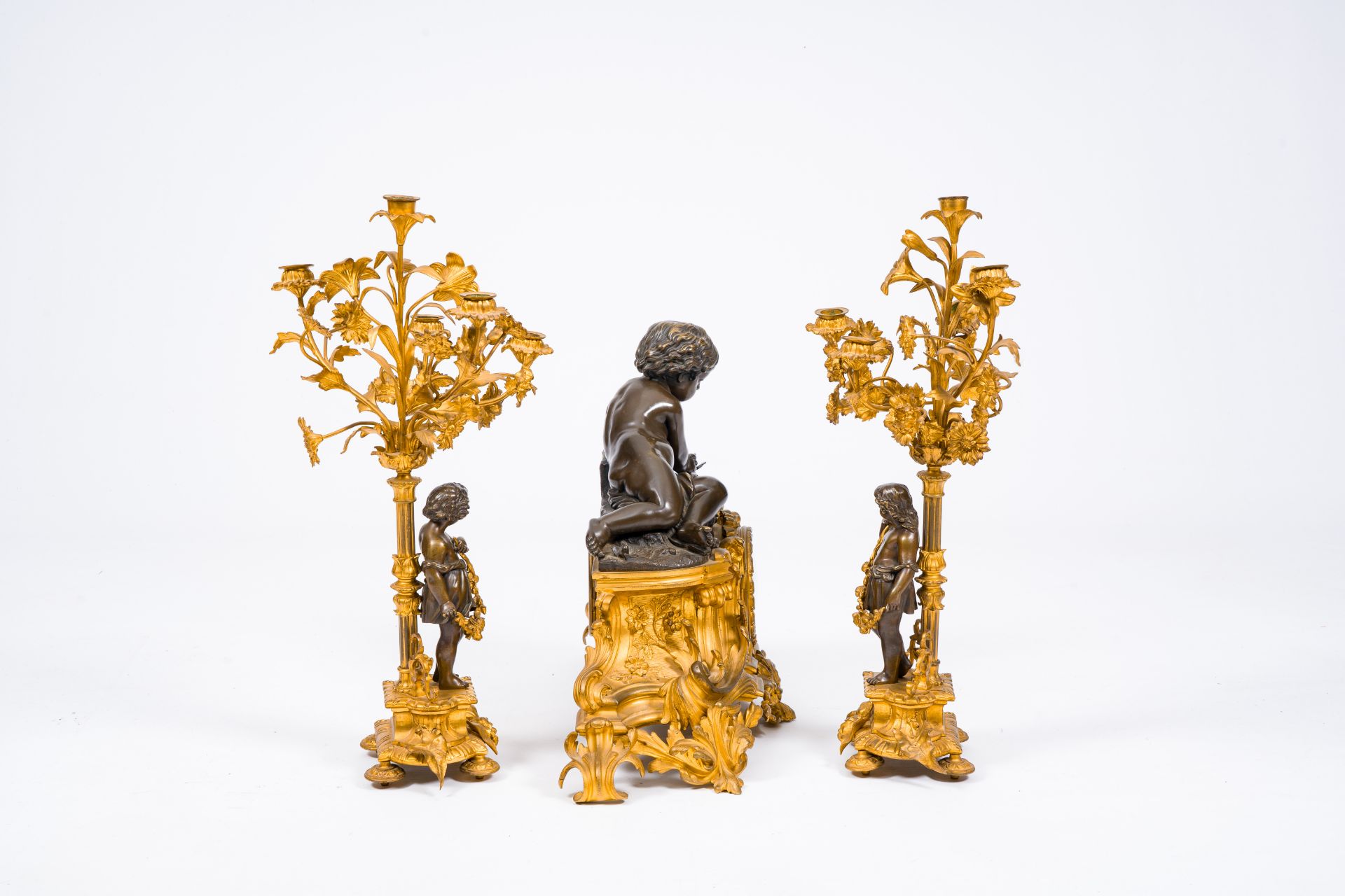 A French gilt and patinated bronze three-piece clock garniture crowned with a putto playing with a b - Image 2 of 5