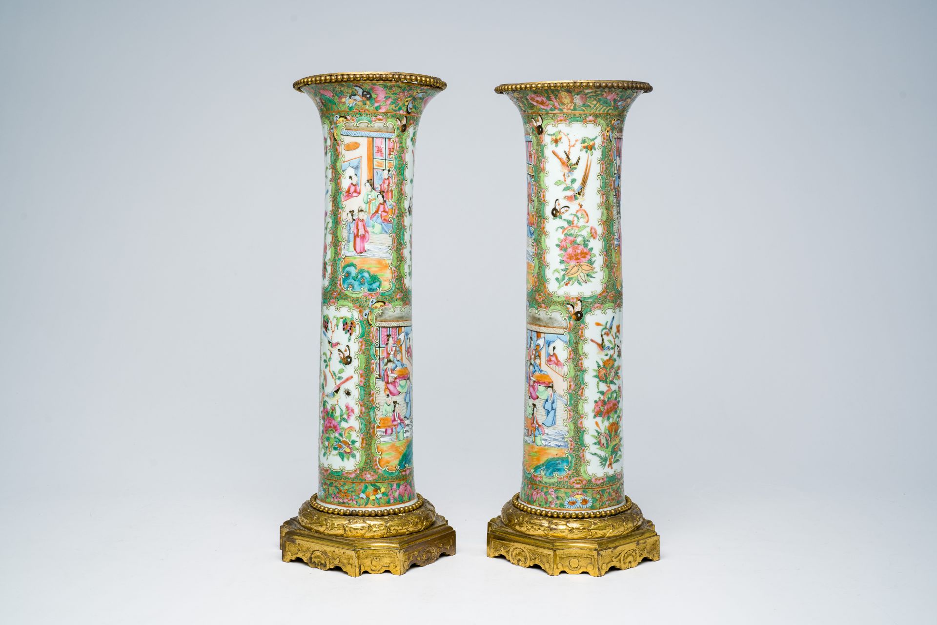 A pair of Chinese Canton famille rose gilt bronze mounted sleeve vases with palace scenes, 19th C.