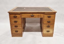 Early 20th century oak desk with leather inset to top, an arrangement of nine drawers around the
