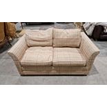 Contemporary two-seater sofa bed by Wesley Barrell, with red and blue check upholstery on a cream