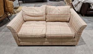 Contemporary two-seater sofa bed by Wesley Barrell, with red and blue check upholstery on a cream