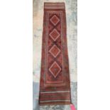 Meshwani red ground wool runner with one row of four lozenge medallions and multiple geometric