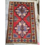 New Baluchi red ground rug with two floral medallions surrounded by multiple geometric shapes and