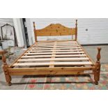 Pine kingsize bed with arched headboard, slatted base, turned supports