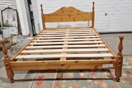 Pine kingsize bed with arched headboard, slatted base, turned supports