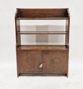 20th century oak shelving unit comprising of three shelves above panelled cupboard doors, on