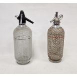 Two vintage soda syphons within metal latticework casing