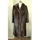 A full length dark mink coat, shawl collar, hook and eye fastening, the hem and cuffs banded