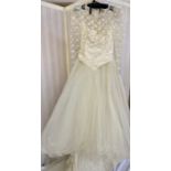 A cream wedding dress with train, lace over a fitted bodice lace full length sleeves,  ruched