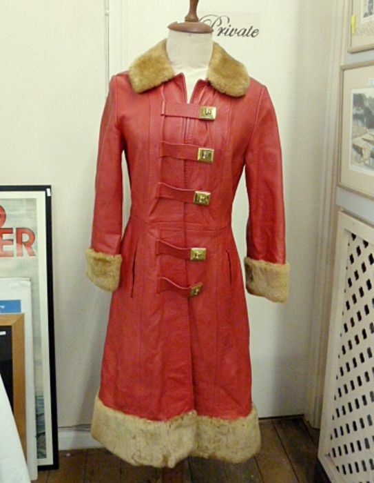 A 1970's red leather coat with brass twist fastening, faux fur collar, cuffs, hem, a black leather