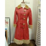 A 1970's red leather coat with brass twist fastening, faux fur collar, cuffs, hem, a black leather