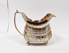 George III silver milk jug, floral scroll with crest of hound holding arrow in mouth, on bun feet,