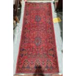 Eastern red ground rug with two central geometric medallions on floral field, multiple floral and