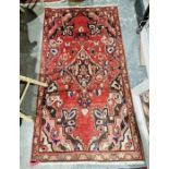 Iranian red ground rug with central floral lozenge, floral spandrels and single floral border