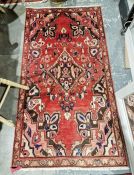 Iranian red ground rug with central floral lozenge, floral spandrels and single floral border