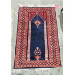 Eastern blue ground prayer rug with two floral pillars enclosing a flower filled vase and hanging