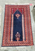 Eastern blue ground prayer rug with two floral pillars enclosing a flower filled vase and hanging