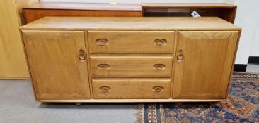 Mid century blonde Ercol sideboard comprising three drawers of graduating form, flanked on either