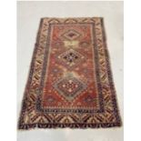 Eastern red ground rug with three central stepped hooked lozenge medallions on geometric field,