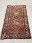 Eastern red ground rug with three central stepped hooked lozenge medallions on geometric field,