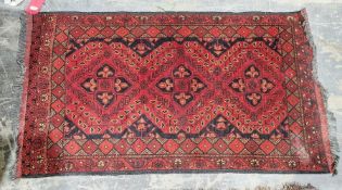 Eastern red ground rug with three central geometric medallions on floral field, multiple floral