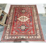 Eastern red ground rug with central floral lozenge flanked by two floral medallions on floral field,