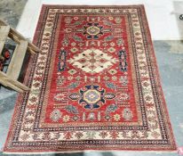 Eastern red ground rug with central floral lozenge flanked by two floral medallions on floral field,