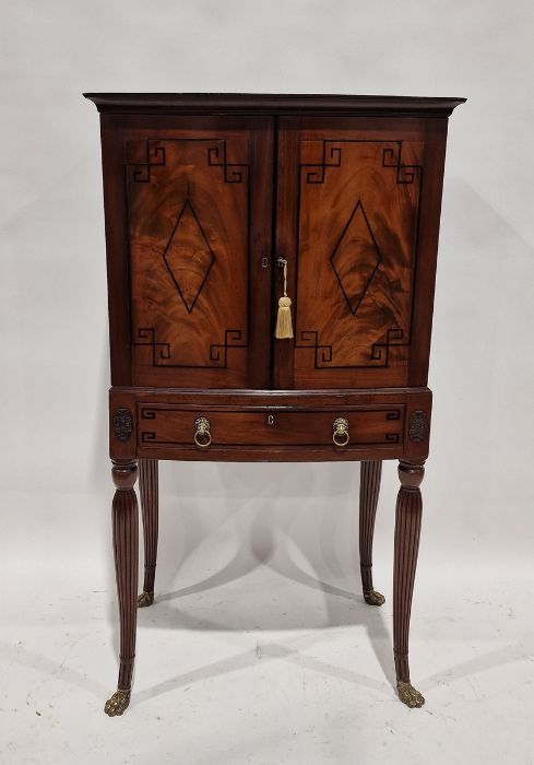 Empire-style bowfronted cabinet on stand, having single shelf enclosed by pair panelled doors with