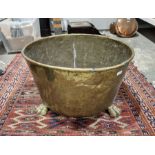 Circular copper log basket with rolled rim supported on three lions paw feet, 36cm high x 58cm