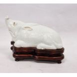 Chinese Export style white glazed porcelain model of a boar on wooden stand, kneeling, in the